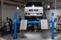 White used car Toyota Hiace van raised on a lift for repairing the chassis and engine in a vehicle repair shop. Auto service