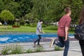 Young brunette teenager guy rides in park on specially designated track, starting with one foot off the ground, standing on other