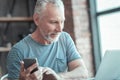 Pleasant senior man holding smartphone and smiling. Royalty Free Stock Photo