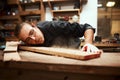 Now for the finishing touch. a focused young male carpenter blowing dust off of a piece of wood after sanding it inside