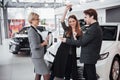 Now her dream comes true. Car salesman giving the key of the new car to the young attractive owners Royalty Free Stock Photo