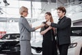 Now her dream comes true. Car salesman giving the key of the new car to the young attractive owners Royalty Free Stock Photo