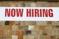 NOW HIRING banner attached to wall