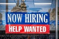 Now Hiring Help Wanted Sign in window of business with ceiling fan visible inside Royalty Free Stock Photo
