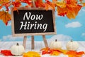 Now hiring sign with standing chalkboard with fall leaves with pumpkins