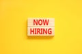 Now hiring symbol. Concept words Now hiring on beautiful wooden block. Beautiful yellow table yellow background. Business