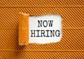 Now hiring symbol. Concept words Now hiring on beautiful white paper. Beautiful brown paper background. Business marketing,