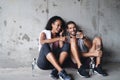 Now this is a jam. a sporty young couple using a cellphone together while sitting down and resting against a wall. Royalty Free Stock Photo