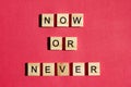 Now or never - the motivating inscription is laid out on a red background with wooden blocks with black letters. Call to action