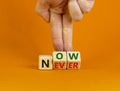 Now or never symbol. Businessman turns wooden cubes and changes the word `never` to `now` or vice versa. Beautiful orange Royalty Free Stock Photo