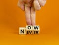 Now or never symbol. Businessman turns wooden cubes and changes the word `never` to `now` or vice versa. Beautiful orange Royalty Free Stock Photo