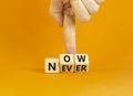 Now or never symbol. Businessman turns wooden cubes and changes the word `never` to `now` or vice versa. Beautiful orange Royalty Free Stock Photo