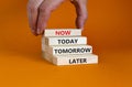 Now or never symbol. Wooden bloks with words `later, tomorrow, today, now`. Businessman hand. Beautiful orange background, copy