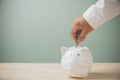 For now, savings money, financial, accounting, and business for future. Man`s hands holding putting coins into a white piggy bank Royalty Free Stock Photo