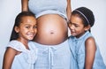 Now there will be three kids. Portrait of two cheerful little girls standing next to their pregnant mother at home Royalty Free Stock Photo