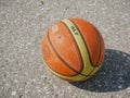 Noyabrsk, Russia - August 9, 2020: An orange and yellow basketball with a shadow on the concrete floor