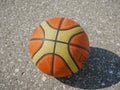 Noyabrsk, Russia - August 9, 2020: An orange and yellow basketball with a shadow on the concrete floor