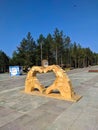 Noyabrsk, Russia - June 20, 2021: Close-up of wooden fingers folded in the form of a heart. Installation in the park. Vertical