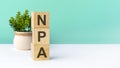 npa - word from wooden blocks with letters, green background. copy space available