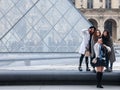 Chinese tourists taking selfie photos in front of the Louvre Pyramid. Louvre pyramid is one of the main attractions of Paris Royalty Free Stock Photo
