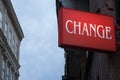 Red sign with the word change written, with buildings in the background, while night is approaching Royalty Free Stock Photo