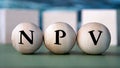 NPV - acronym on wooden balls on the background of wooden large cubes Royalty Free Stock Photo