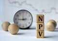 NPV - acronym on wooden cubes on graph, clock and wooden balls background Royalty Free Stock Photo