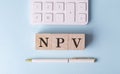 NPV on wooden cubes with pen and calculator, financial concept Royalty Free Stock Photo