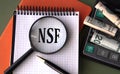 NSF - acronym under magnifying glass on the background of calculator and banknotes Royalty Free Stock Photo