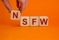 NSFW - not safe for work symbol. Wooden cubes with the word `NSFW - not safe for work` on beautiful orange background, copy spac