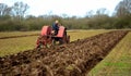 Ntage red International 1930`s tractor ploughing field. Royalty Free Stock Photo