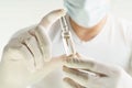 Male hands in latex gloves holding a syringe on dark background