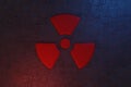 Nuclear energy radioactive ionizing atomic radiation round symbol shape painted on massive metal wall texture dark background.