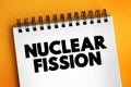 Nuclear fission - reaction in which the nucleus of an atom splits into two or more smaller nuclei, text concept on notepad