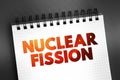 Nuclear fission - reaction in which the nucleus of an atom splits into two or more smaller nuclei, text concept on notepad