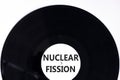 Nuclear fission symbol. Concept words Nuclear fission on beautiful black vinyl disk. Beautiful white table white background.