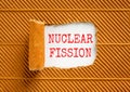 Nuclear fission symbol. Concept words Nuclear fission on beautiful white paper. Beautiful brown paper background. Business science