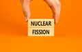 Nuclear fission symbol. Concept words Nuclear fission on beautiful wooden blocks. Beautiful orange table orange background.