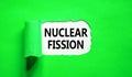 Nuclear fission symbol. Concept words Nuclear fission on beautiful white paper. Beautiful green paper background. Business science