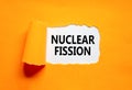 Nuclear fission symbol. Concept words Nuclear fission on beautiful white paper. Beautiful orange paper background. Business