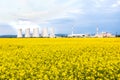 Nuclear power plant with cooling towers behind yellow rapeseed field Royalty Free Stock Photo