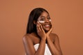 Nude black woman applying eye cream after shower Royalty Free Stock Photo