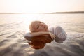 Nude naked sexy woman in water at sunset. Beautiful blonde woman with short wet hair and big breasts, art portrait in sea