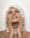 Nude senior woman toothy smiling touching her face with her hands. Naked mature woman with pearl beads around her neck Royalty Free Stock Photo