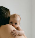 Nude woman with baby in her arms on lighte background. Happy motherhood and breastfeeding concept. Photos with soft focus. Good