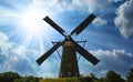 Ancient historical rural dutch windmill with backlight of sun rays, blue summer sky fluffy clouds