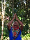 Elderly indigenous shaman of Cofan nationality performing a healing ritual with his arms raised in the Amazon jungle seen from the