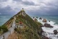 The steep headland of Nugget Point with Nugget Point Lighthouse and rocky islets called The Nuggets at the Catlins, New Zealand.