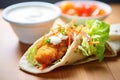 nuggets inside a pita pocket with lettuce and tomato