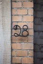 Number 28 antique wrought iron house number on brick wall Royalty Free Stock Photo